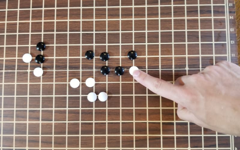 An image shows the placement of stones in a game of go after a few moves have taken place.